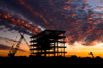 Steel construction site at sunset with a crane.