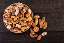 Top View Of Organic Raw Nuts Mix Of Pistachios, Almonds, Walnuts, Dried Mulberries, Dried Figs And Hazelnuts On Wooden Plate And Table Background, Healthy Natural Trail Mix Snack, Shot From Above