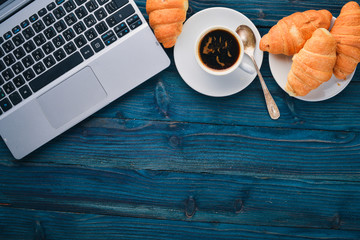 Business breakfast, coffee and croissants, on a wooden surface. Top view. Free space for text.