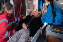 Cropped Image Of Paramedics Moving Unconscious Man Into Ambulance