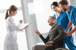 © LIGHTFIELD STUDIOS - Doctor talking with middle aged patient on wheelchair