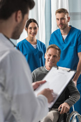 smiling mature patient on wheelchair listening doctor