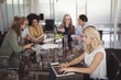 © WavebreakMediaMicro - Young businesswoman using laptop on conference table with team