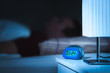 Man sleeping in bed. Digital alarm clock on nightstand in bedroom. Dreamy blur effect.