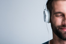 Perfect Song. Part Of Portrait Of Handsome Young Man Listening To Music In Headphones With Smile While Standing Against White Background