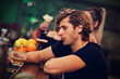 © Kalim - Young man sitting alone in bar with a glass of whisky