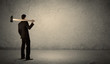 © ra2 studio - Business man standing in front of a grungy wall with a hammer