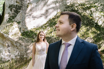 Young bride and groom walking high in mountains. Amazing weather with fog and sun