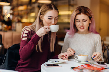 Two girls meat at coffee place and talk to each other, make conversation