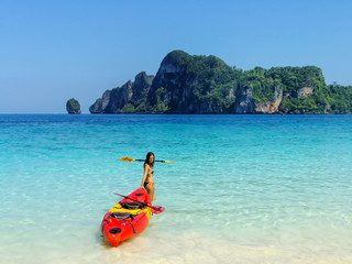 Wall Mural - Young woman standing with kayak at Ao Yongkasem beach on Phi Phi Don Island, Krabi Province, Thailand