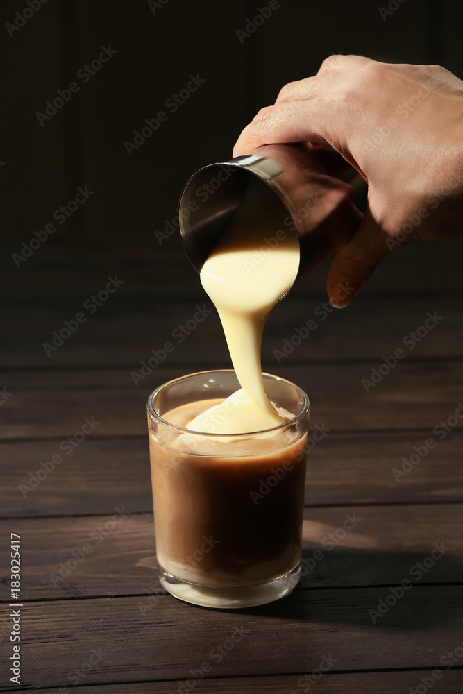 Woman adding condensed milk to coffee at table