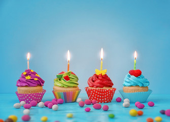 Canvas Print - Festive bright cupcakes with candles on color background