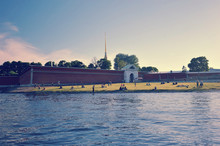 People Sunbathing On The Lawn In Front Of The Entrance To The Peter And Paul Fortress In Saint-Petersburg