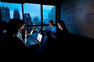 working overtime concept. group of young business team working late at night in meeting room trying 