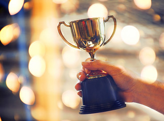 Wall Mural - winner 's hand hold trophy with bokeh light background