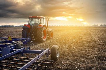 Aufkleber - Tractor working in the field on a sunset background