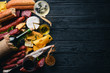© Yaruniv-Studio - A bottle of wine, cheeses and traditional sausages on a wooden background. Brie cheese, blue cheese, gorgonzola, fuete, salami. Free space for text. Top view.