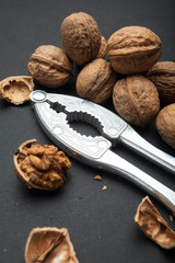 Wall Mural - Fruits of a walnut on a black table close up. Whole and open, the core of the nut. Nutcracker.