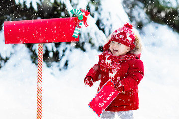 Wall Mural - Child with letter to Santa at Christmas mail box in snow