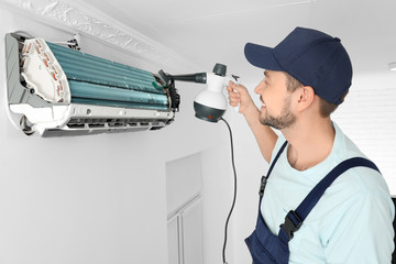 Wall Mural - Male technician cleaning air conditioner indoors