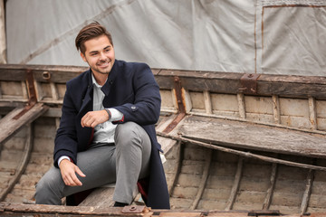 Poster - Young handsome man sitting in old boat, outdoors