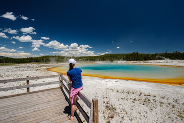 Wall Mural - Woman tourist overlooking thermal spring in Yellowstone