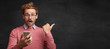 © WHstudio Leushin N - Shocked male student uses modern smart phone, messages with friend, notices something strange behind, isolated over black chalk background. People, technology, emotions and advertising concept