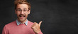 © wayhome.studio  - Cheerful male nerd in spectacles stands against chalkboard, points with thumb on copy space for your advertising content. Horizontal shot of glad college professor shows something at blackboard