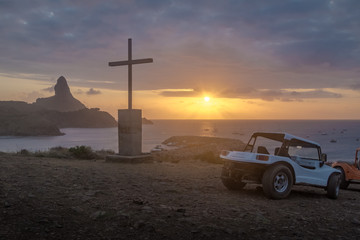 Wall Mural - Buggies and Sunset View from Chapel of Sao Pedro dos Pescadores with Morro do Pico on background - Fernando de Noronha, Pernambuco, Brazil