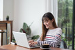 © weedezign - Asian woman using on laptop computer near window at cafe restaurant,Digital age lifestyle,using Technolgy  concept,co working space.