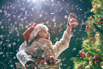 child decorating christmas tree