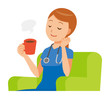 A woman nurse in a blue scrub is sitting on a sofa and drinking coffee