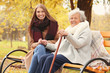 © Africa Studio - Senior woman with cane and young caregiver sitting on bench in park
