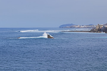 Canvas Print - Waves break on small rocks in the middle of the bay.