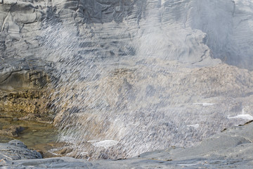 Wall Mural - Wave breaks on the rock forming a splash wall.