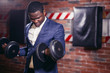 Portrait Sexy african man in classic suit working out with dumbbells in gym.