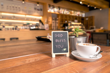 Wall Mural - A cup of coffee in relax time on wood table beside mini blackboard with wish text 