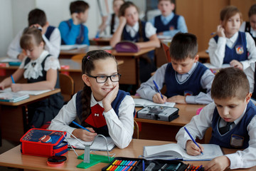 Wall Mural - Elementary school students at a lesson in school writing in notebooks