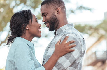 Wall Mural - Affectionate young African couple standing together outside