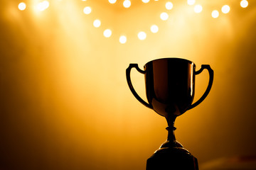 Wall Mural - gold trophy competition in the dark on the abstract blurred light background with copy space, specta