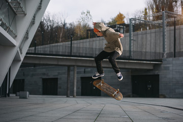 Wall Mural - Skateboarder in streetwear outfit performing jump trick in urban location