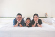 © Phawat - Asian Family Lovely lie about puckering lips and Pose hands on chin on white bed with copy space