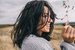 © iuricazac - Side view portrait of happy brunette young woman wearing gray sweater being playful and carefree with beautiful smile  and windy hair posing on landscape. Lifestyle concept. Cover idea mood.