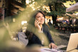 © liderina - Smiling young woman talking on phone at cafe.