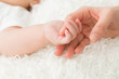 赤ちゃんと手をつなぐ女性
