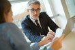 Woman in banker's office signing financial loan for project