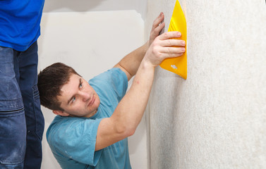 Wall Mural - young worker smoothing wallpaper