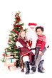 © Mediaphotos - Santa Claus sitting in chair near Christmas tree with multi-ethnic boy and girl on his lap
