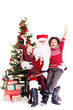 © Mediaphotos - Santa Claus sitting in chair near Christmas tree with multi-ethnic boy and girl on his lap