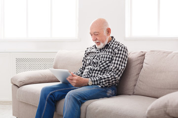 Senior man reading news on digital tablet